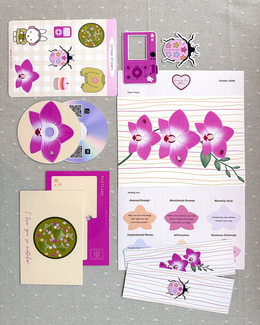 a pink orchid art print, ladybug and digital camera vinyl stickers, sticker sheet, matcha postcard, ladybug and orchid double sided bookmark, CD playlist print, and letter all printed and laid out on a table 